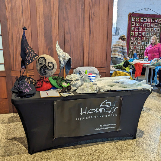 Table of finished wet felted hats made of Irish-grown wool and Merino, along with a wet felting demo area.