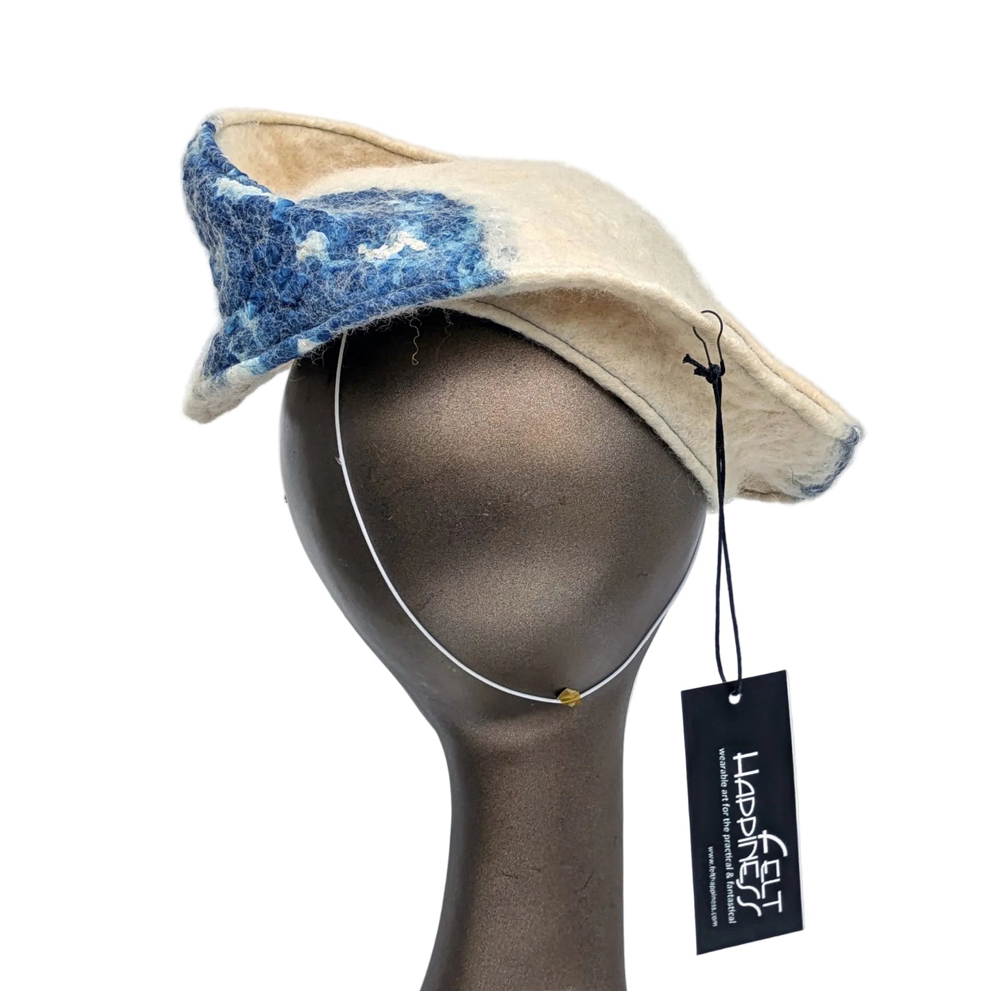 Cream and blue patterned fascinator on a mannequin head against a white background
