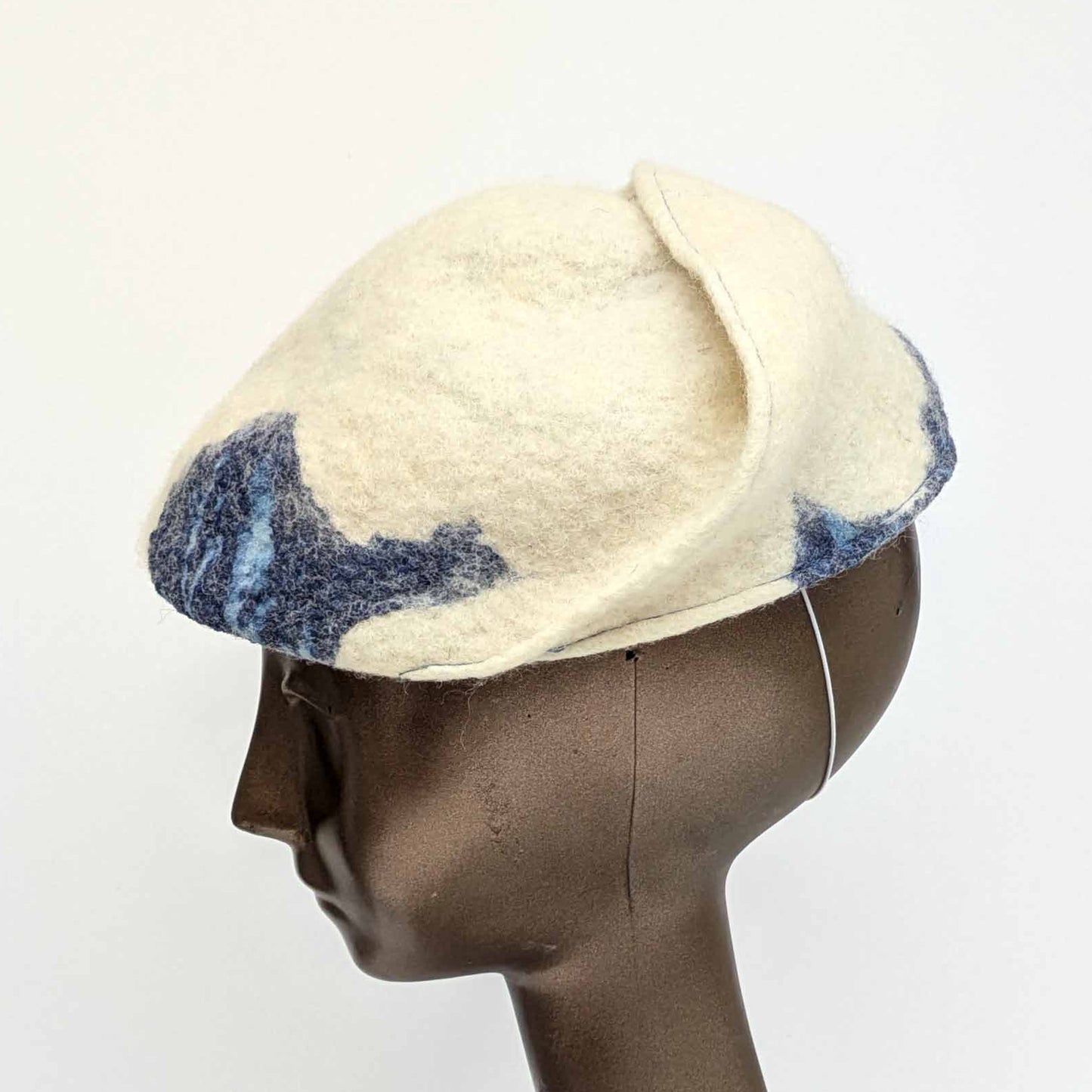 Cream coloured fascinator with blue cyanotype decorative pattern - worn on a mannequin - side view
