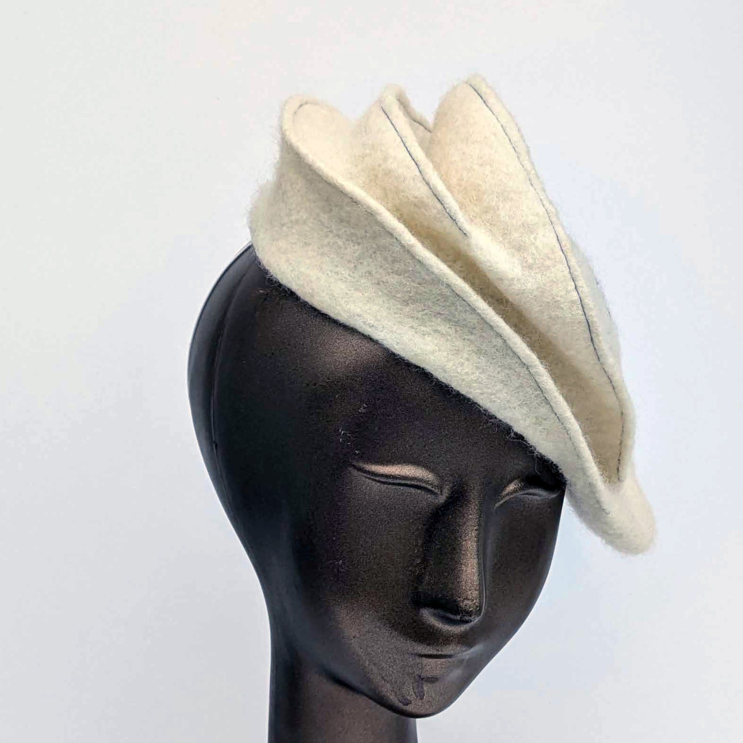 Cream coloured felt fascinator with topstitching.