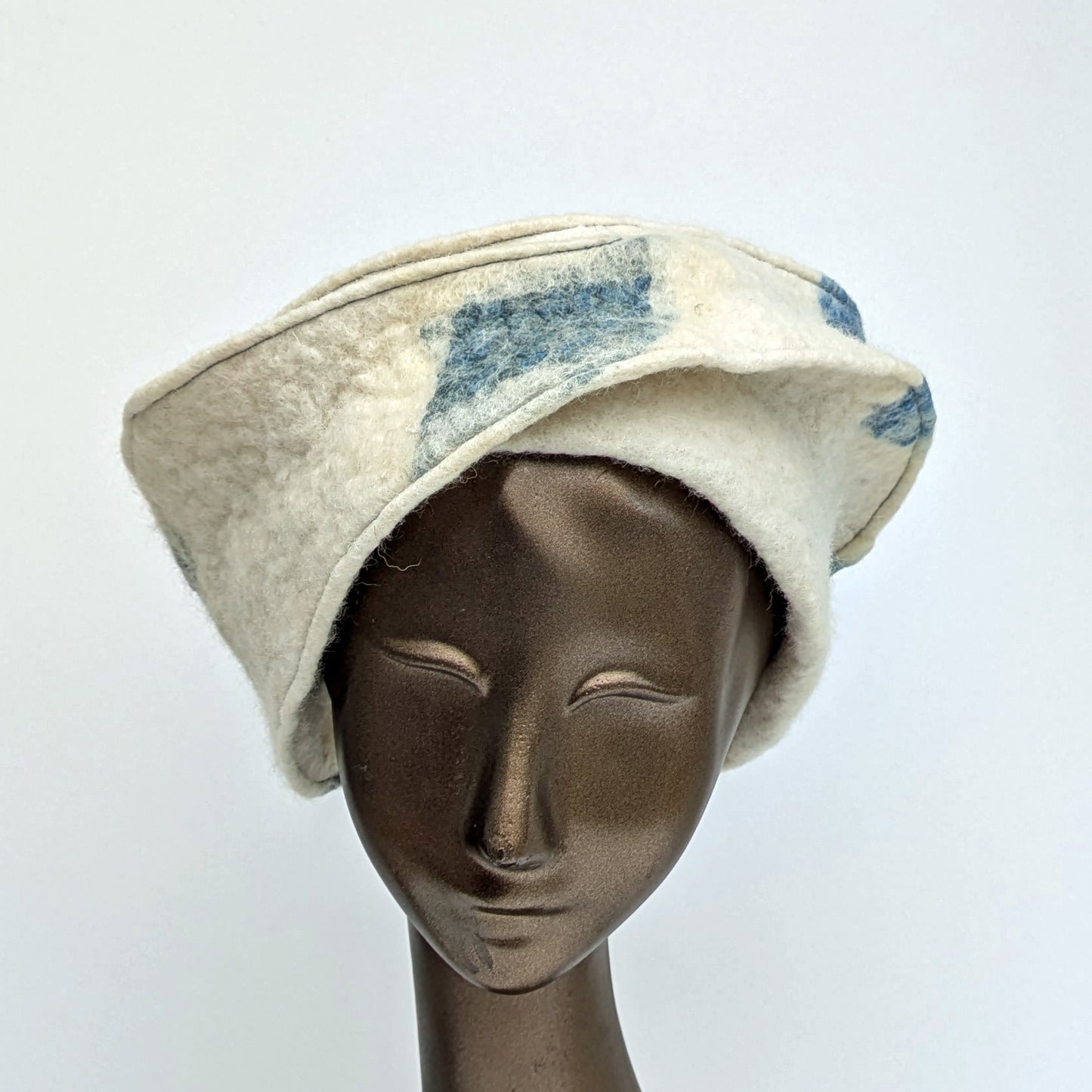 Creamy white hat with diagonal lines and blue-coloured diamond shape on the front.