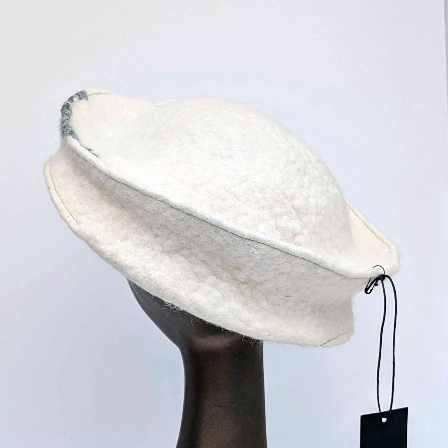 Cream coloured, asymmetrical hat with a broad band - backview.