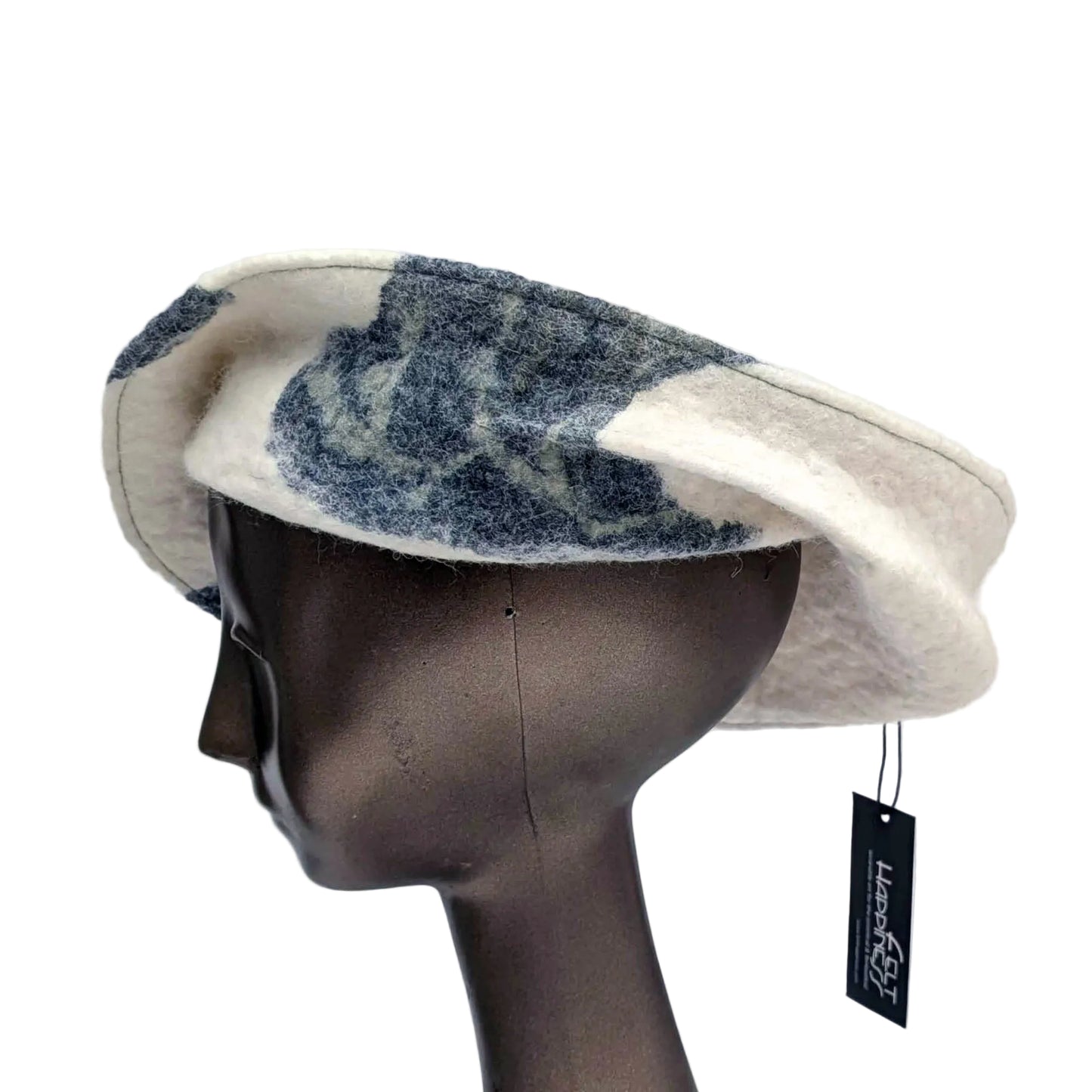 Asymetrical cream coloured hat with sections of dark blue botanical patterning.