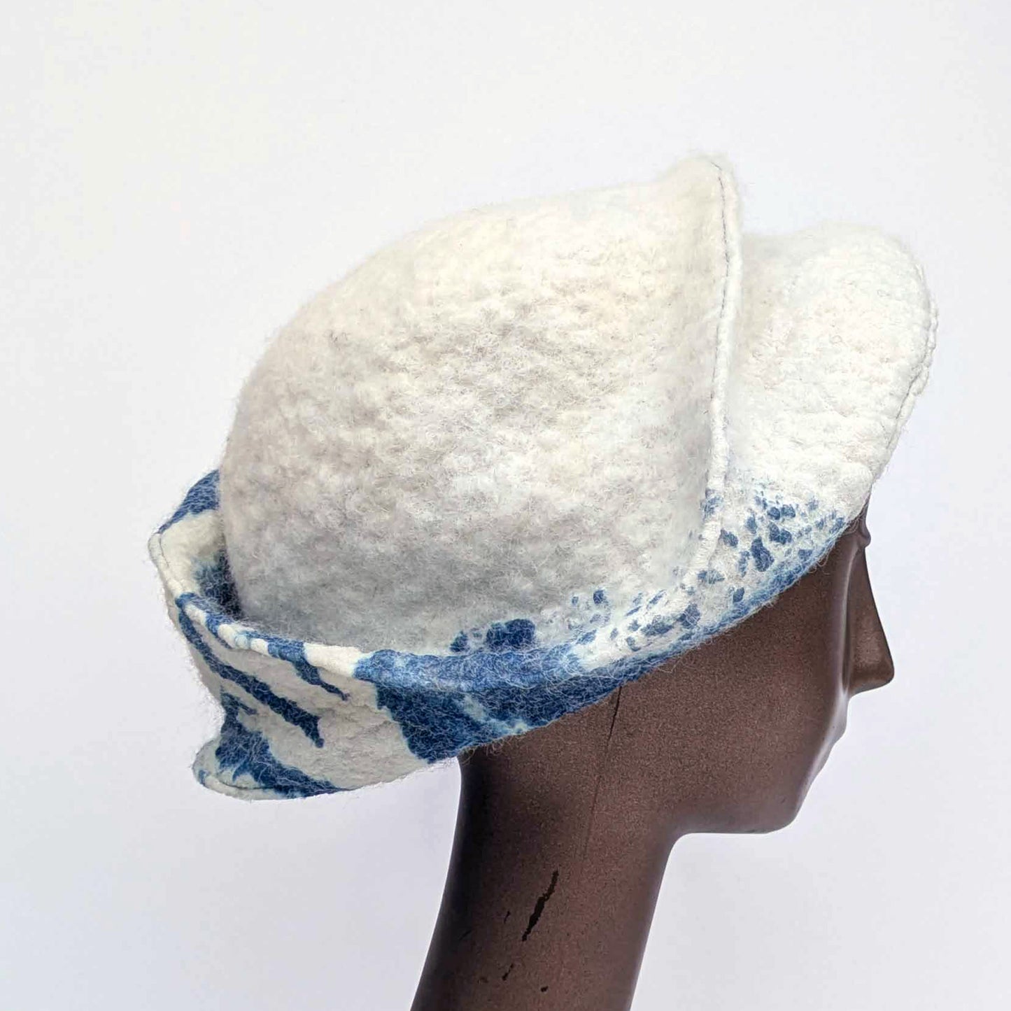 White and blue patterned hat on a mannequin head against a white background