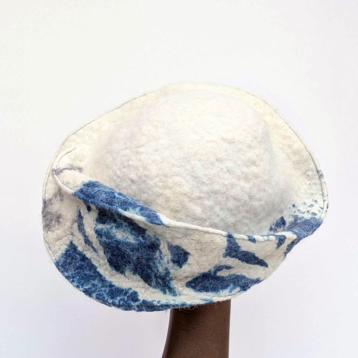 White and blue patterned hat on a mannequin head against a white background -backview