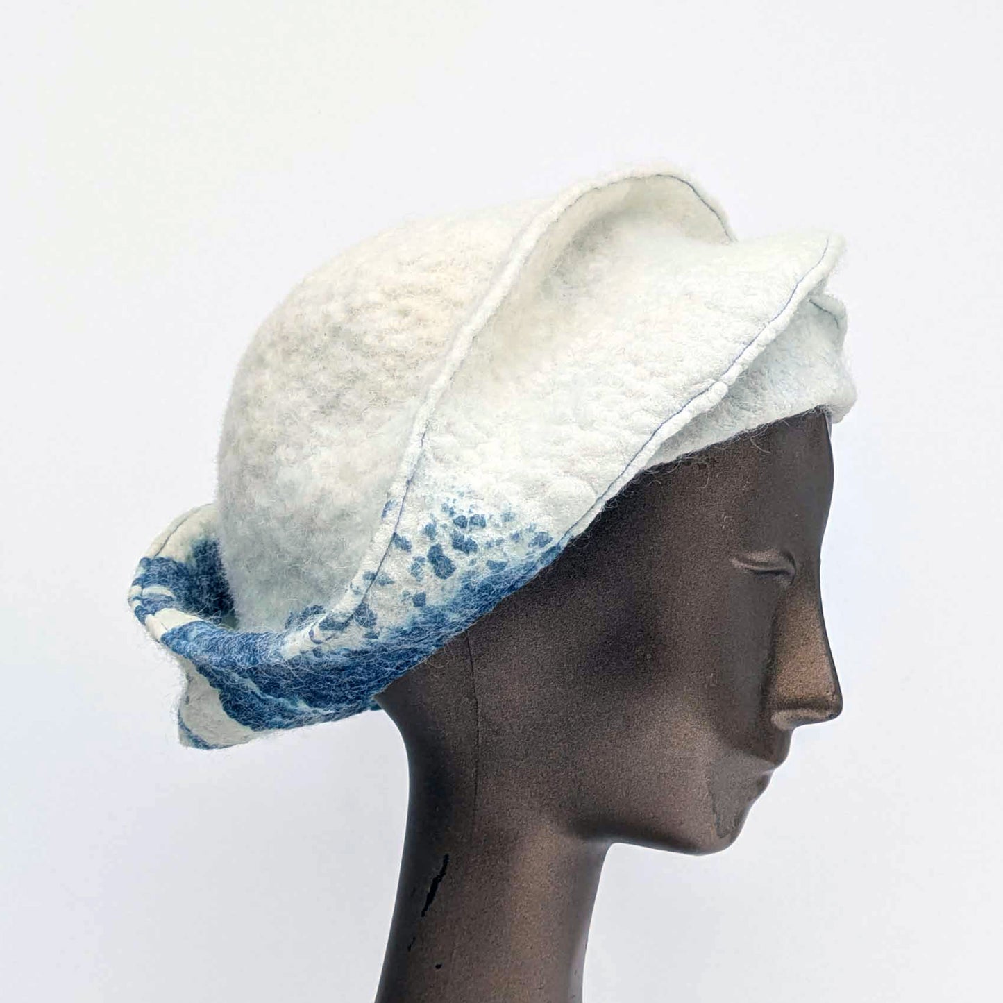 White and blue patterned hat on a mannequin head against a white background