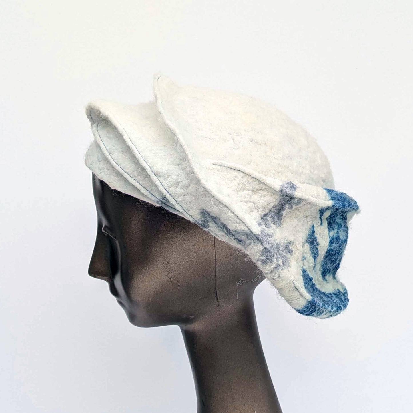 White and blue patterned hat on a mannequin head against a white background