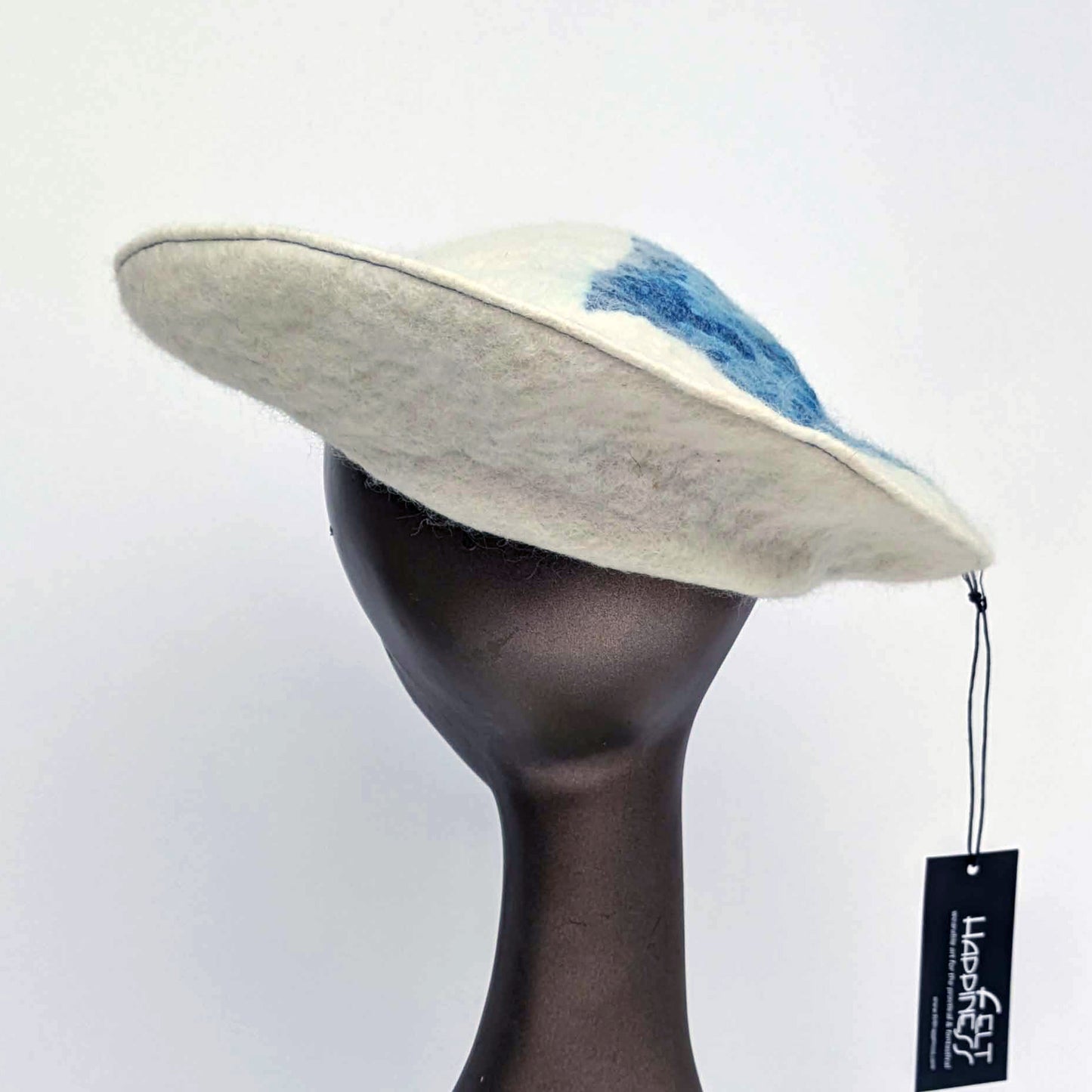 White beret with blue seaweed pattern on tipof hat - worn on mannequin - back view