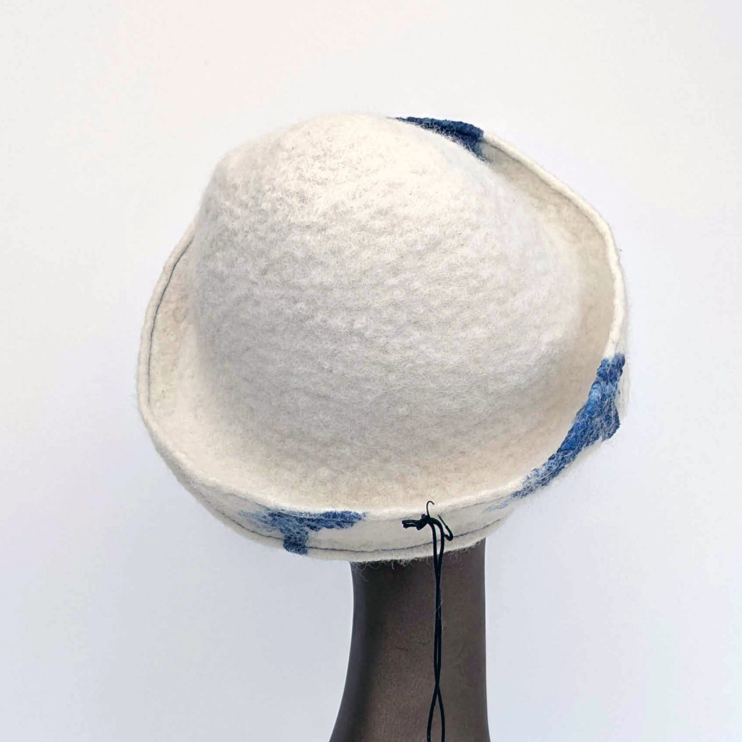 White cap with small bill and blue decorative elements on a mannequin head against a white background - backview