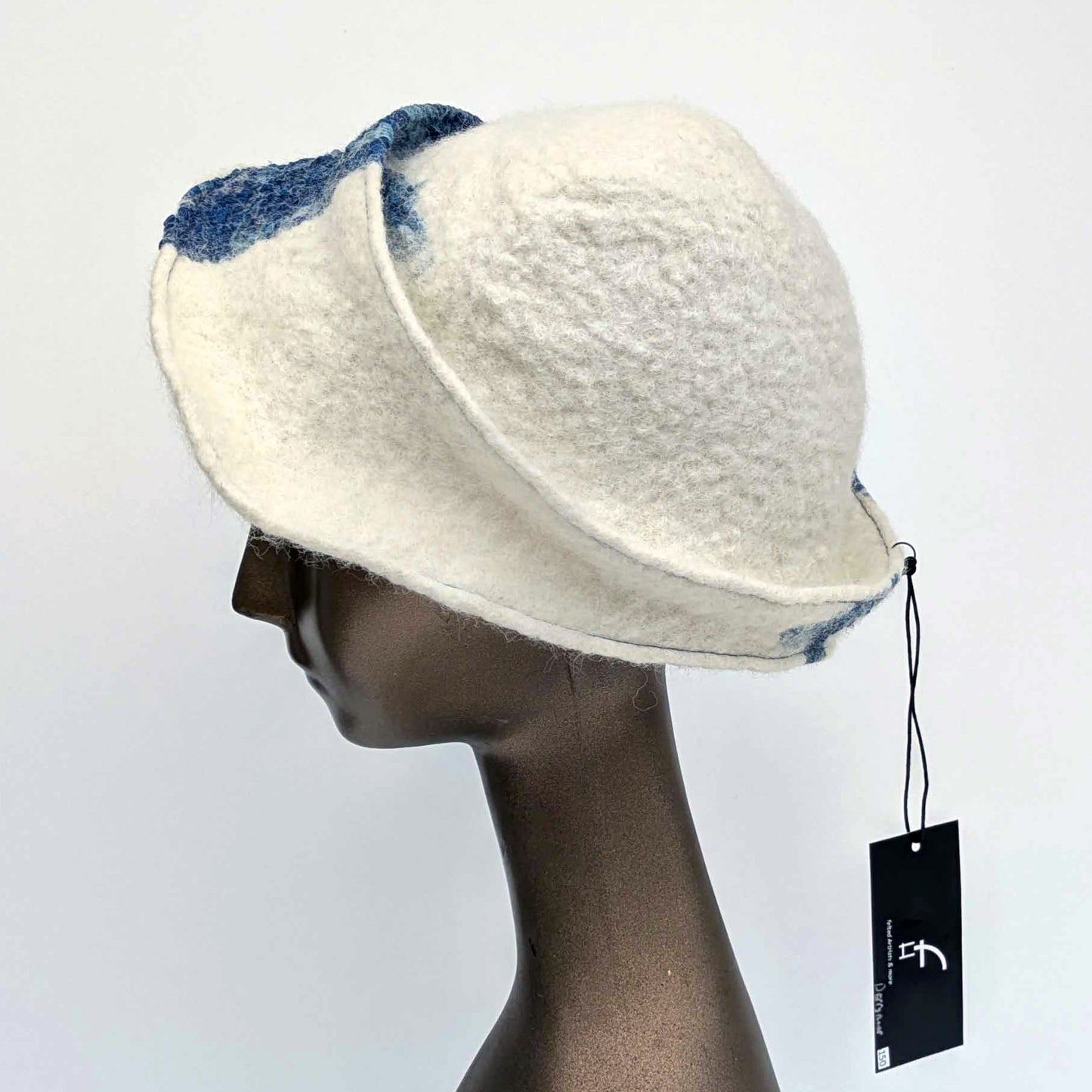 White cap with small bill and blue decorative elements on a mannequin head against a white background - side view