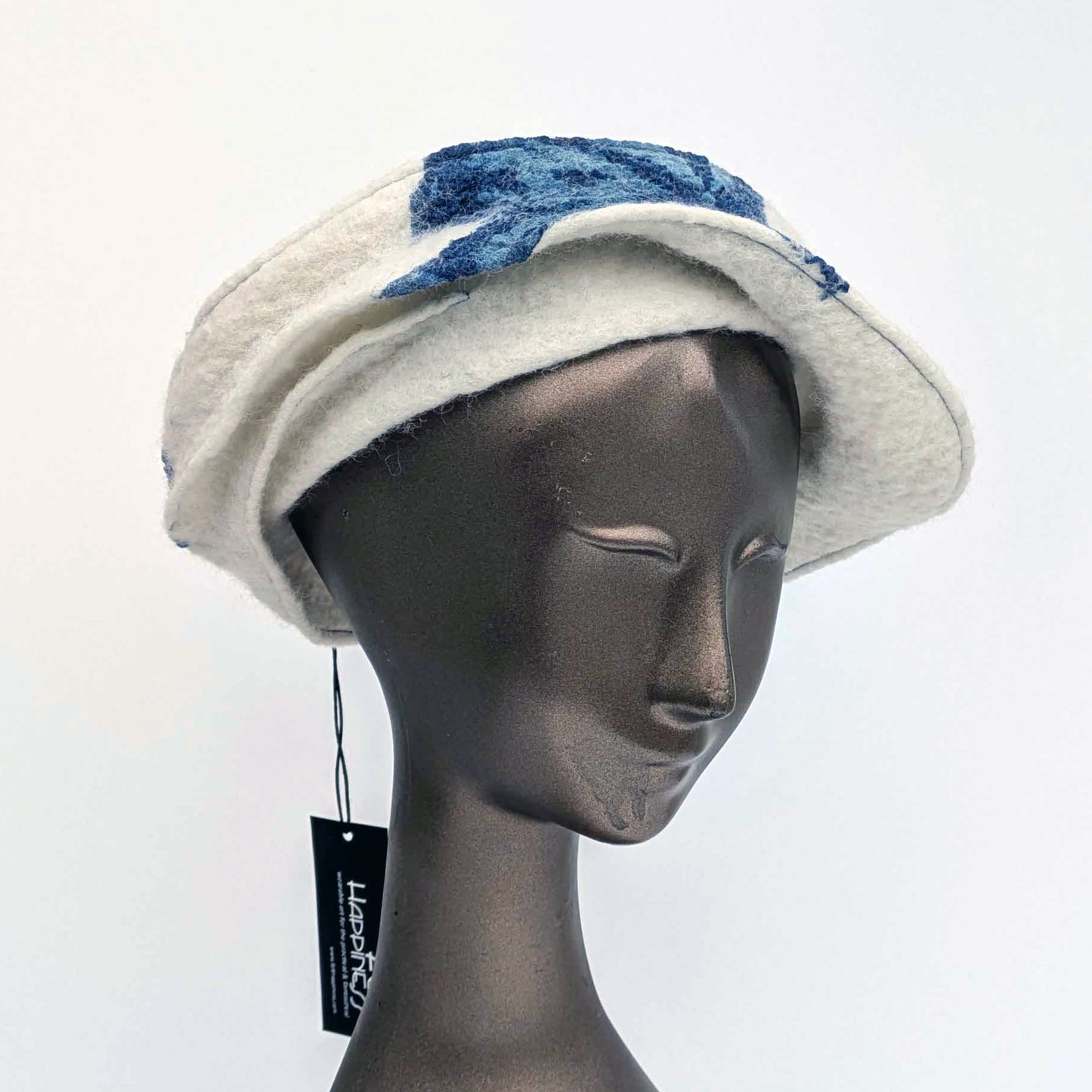 White cap with small bill and blue decorative elements on a mannequin head against a white background