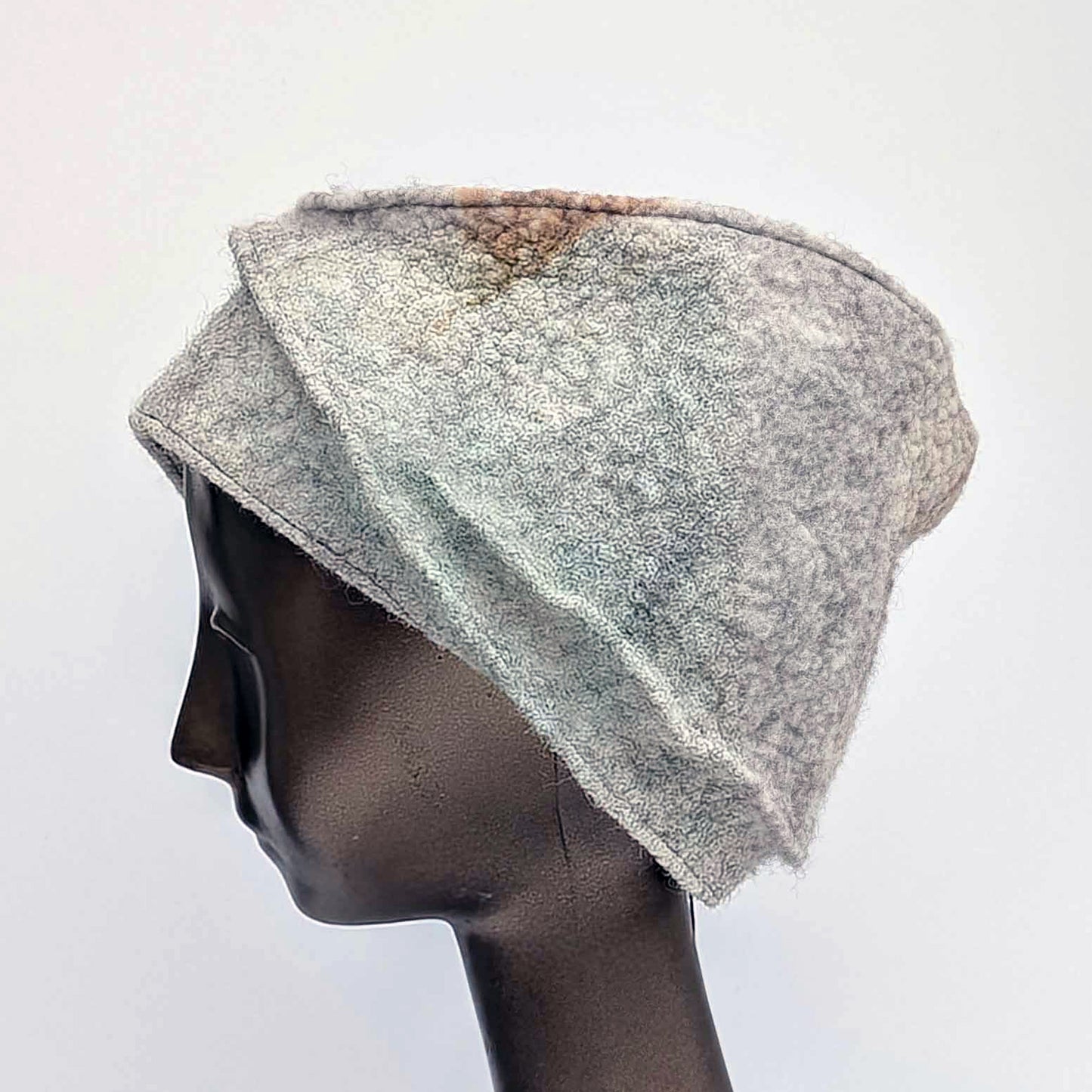 Grey cloche hat on a mannequin head against a white background. Side view.
