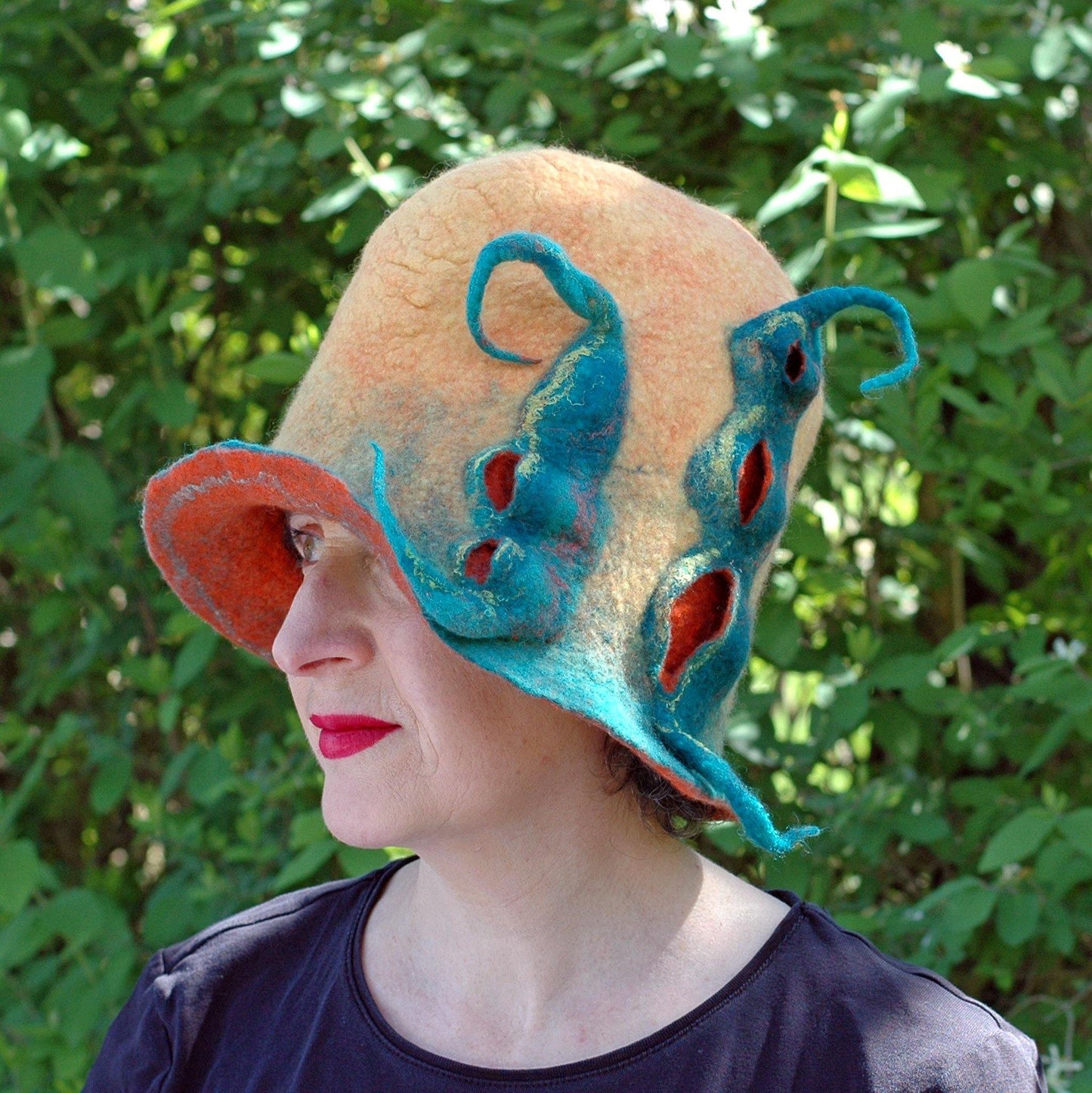 Oversized Yellow Orange and Green Hat with Rounded Top - against the shrubbery