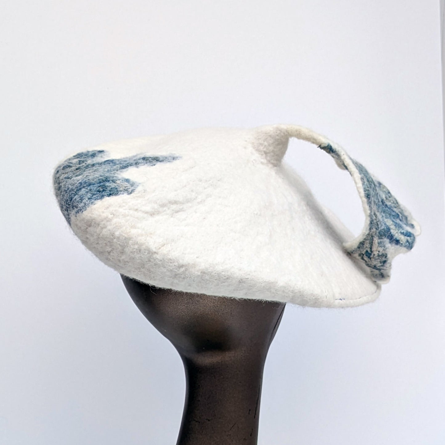 Back view of beret with blue-green leafy tassel -worn by mannequin.
