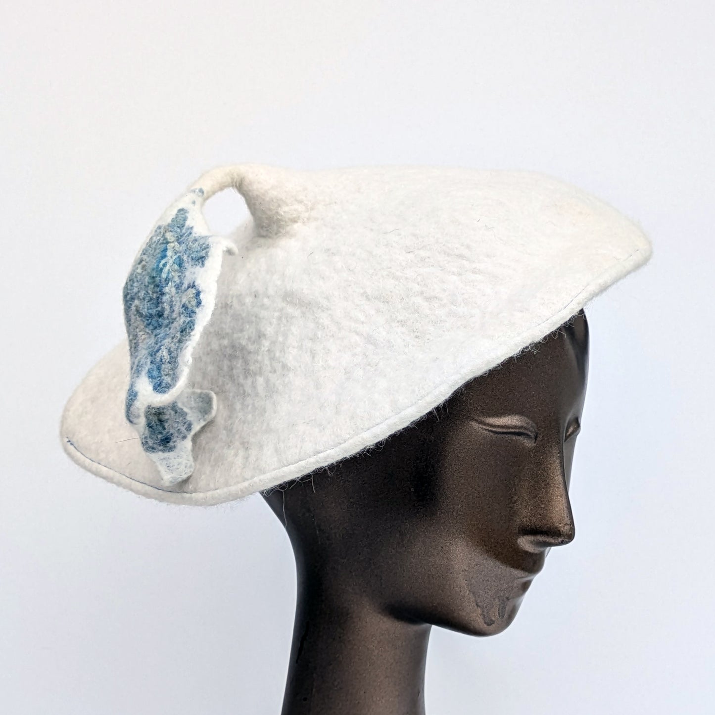 White beret with blue-green-coloured tassel - worn by mannequin.