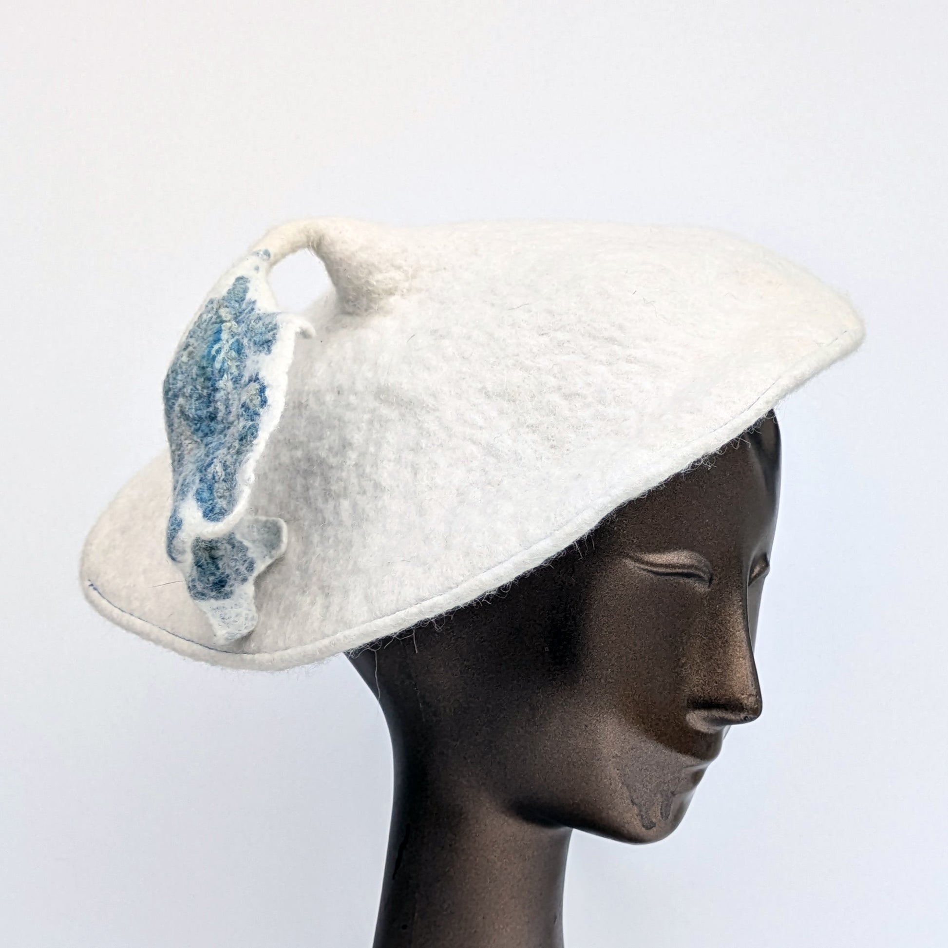White beret with blue-green-coloured tassel - worn by mannequin.