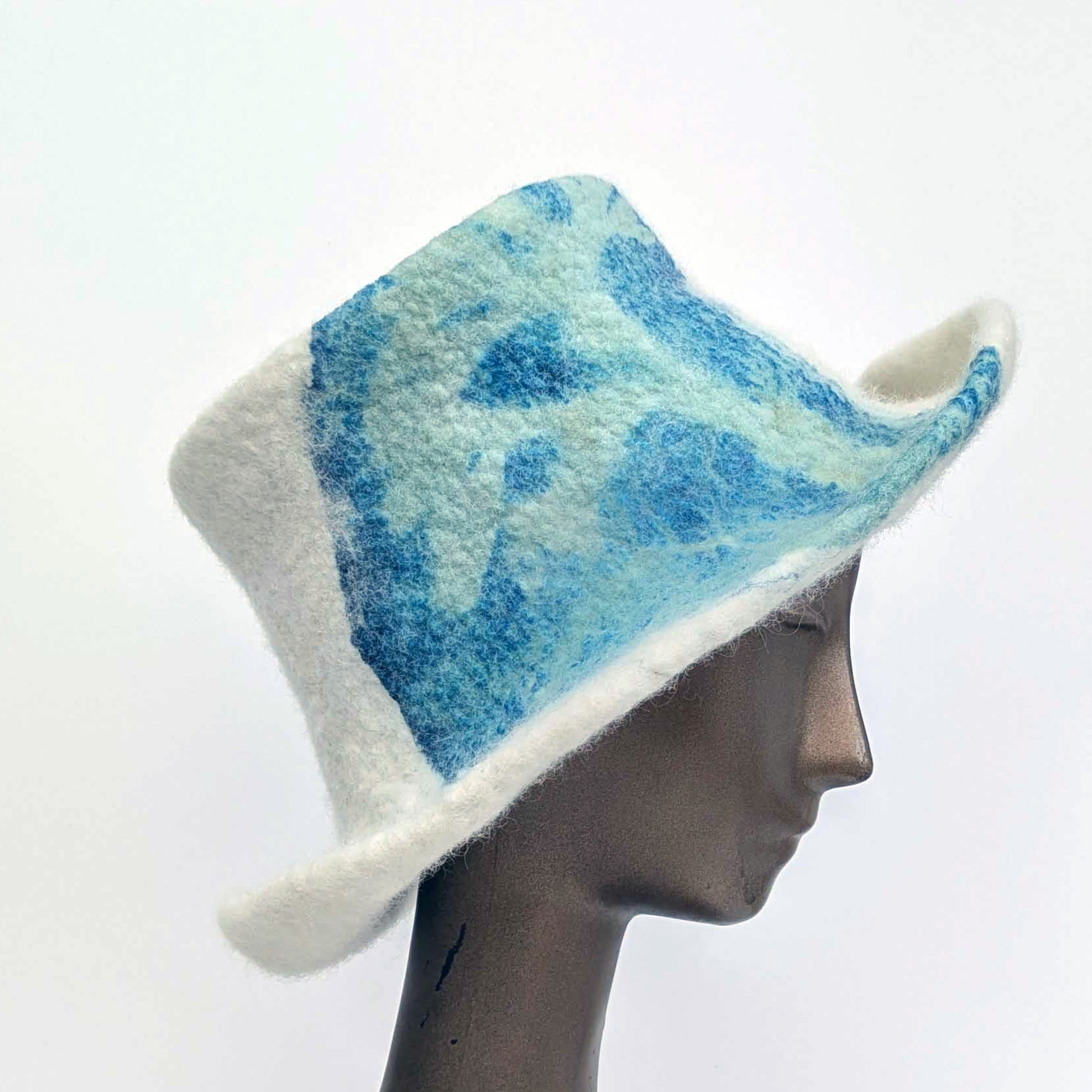 Cream-coloured top hat with wide brim and sage green seaweed print against blue Cyanotype - side view