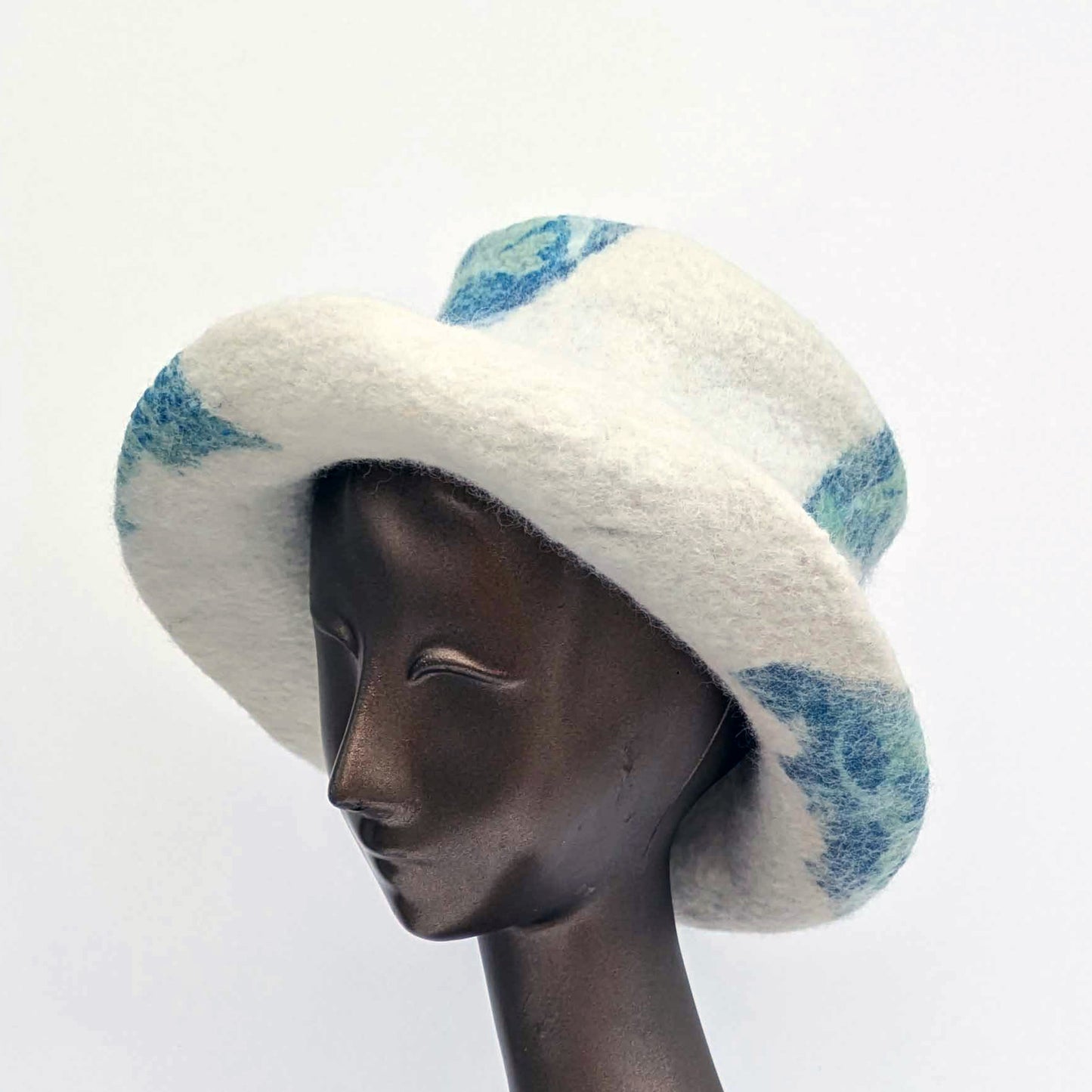 Cream-coloured top hat with wide brim and sage green seaweed printsagainst blue Cyanotype - three quarters view