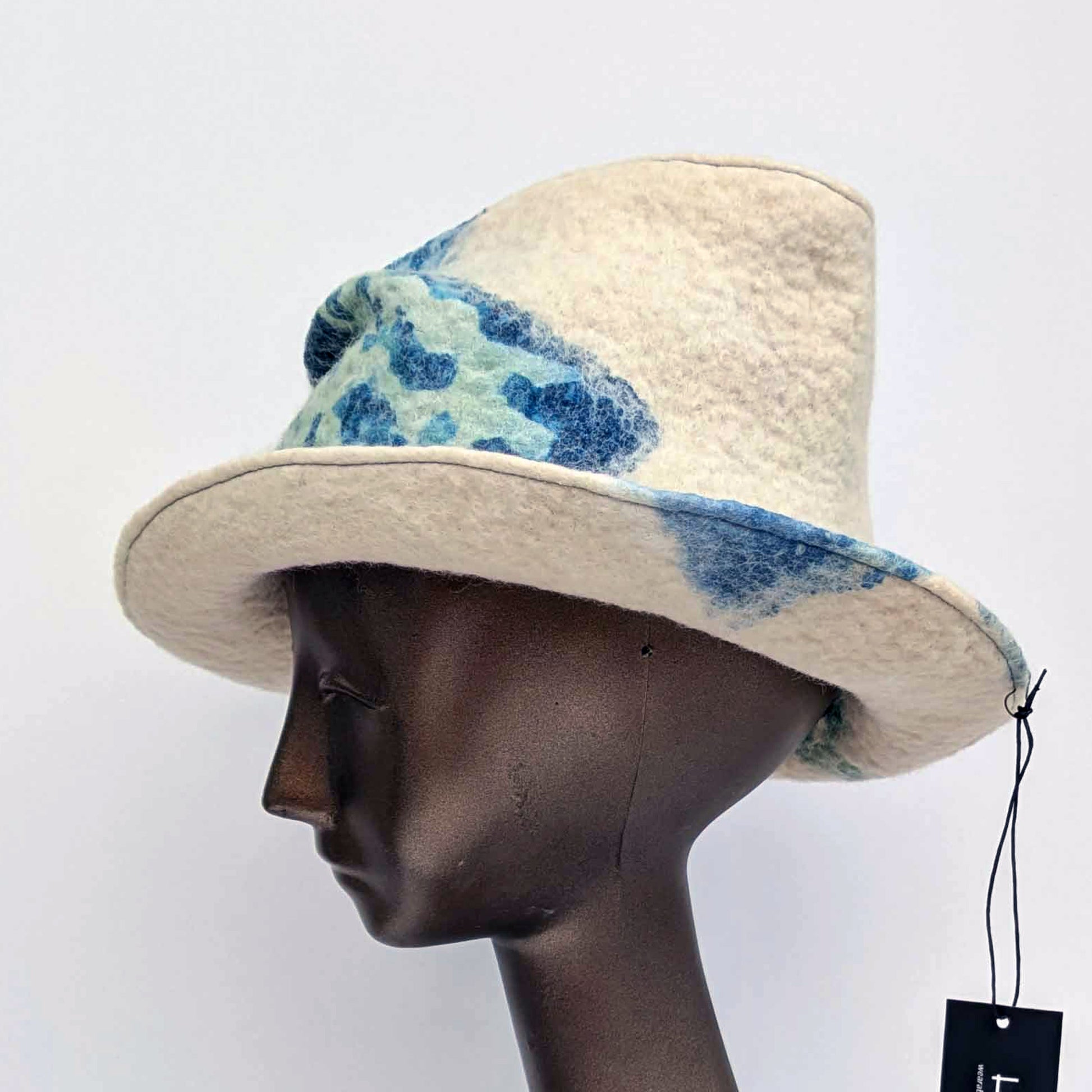 "Crushed' tip, Fedora hat with blue and green pattern on a mannequin head against a white background - side view.