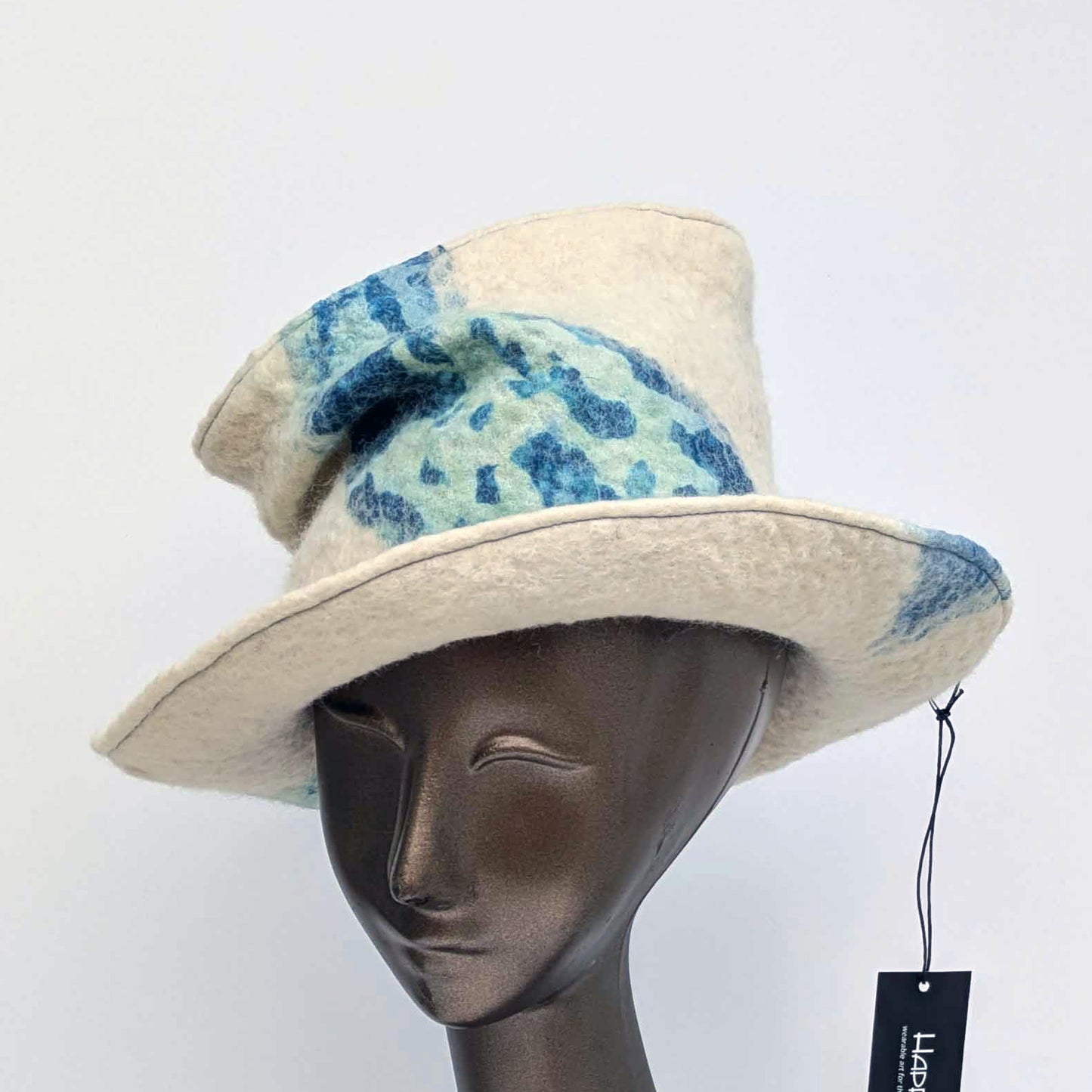 "Crushed' tip, Fedora hat with blue and green pattern on a mannequin head against a white background - threequarters view