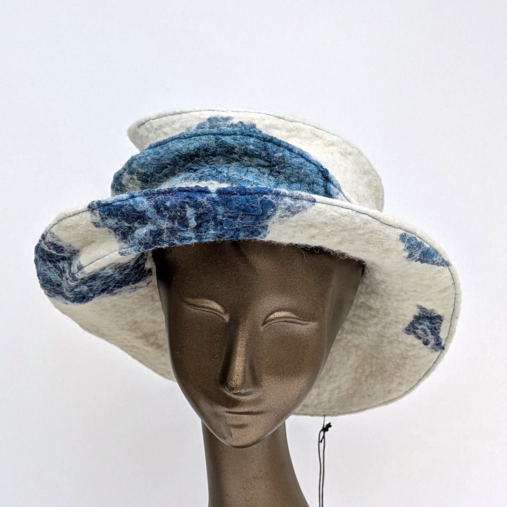 Wide brimmed, cream-coloured hat with indigo-blue silk felted in - worn on mannequin