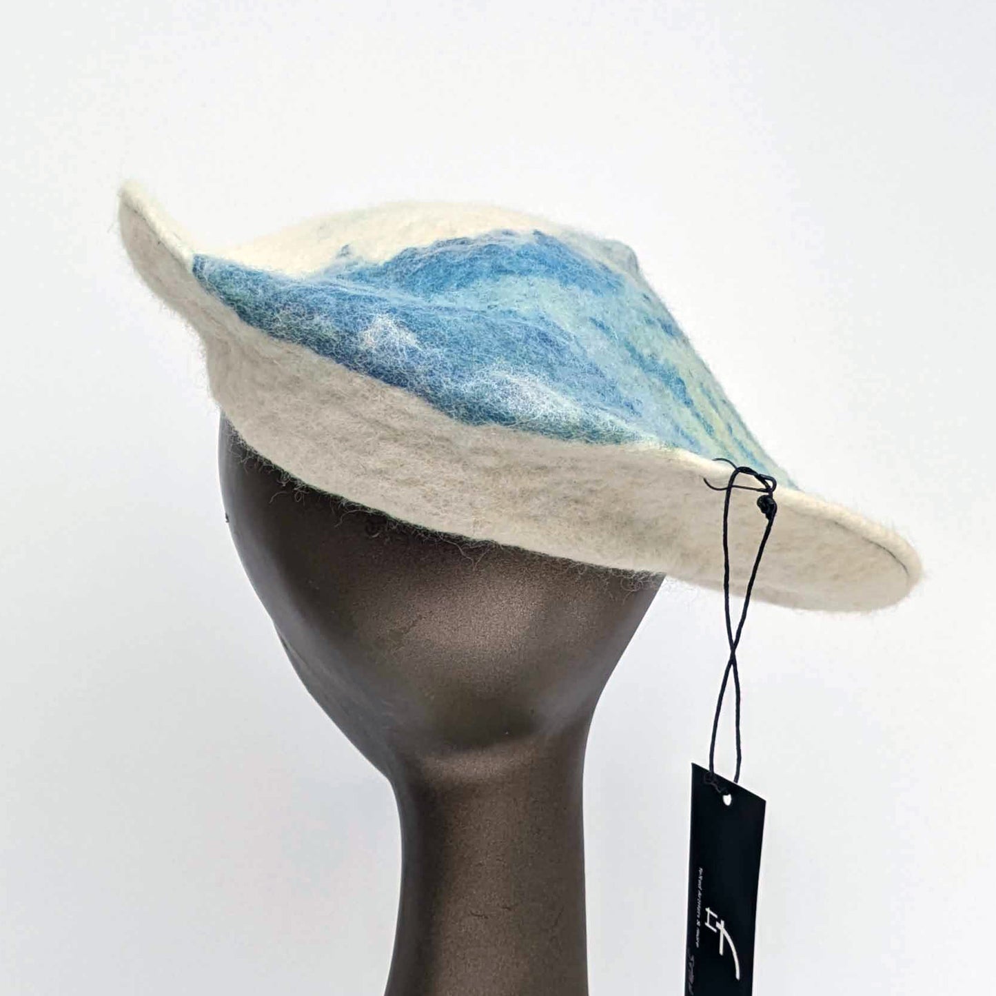 Cream coloured saucer beret hat with blue seaweed Cyanotype print on the tip - worn by a mannequin.  Back view
