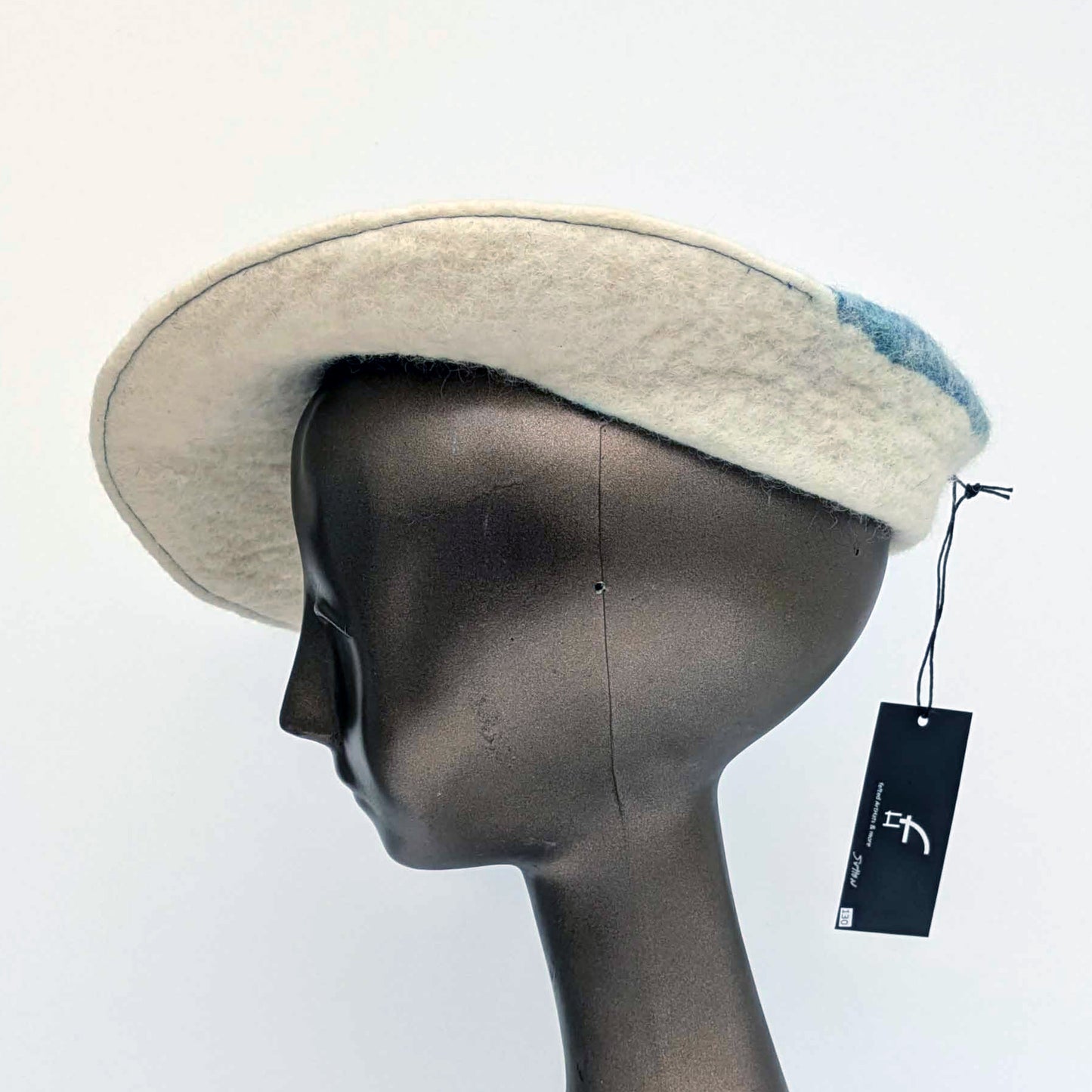 Cream coloured saucer beret hat with blue seaweed Cyanotype print on the tip - worn by a mannequin.  Side view