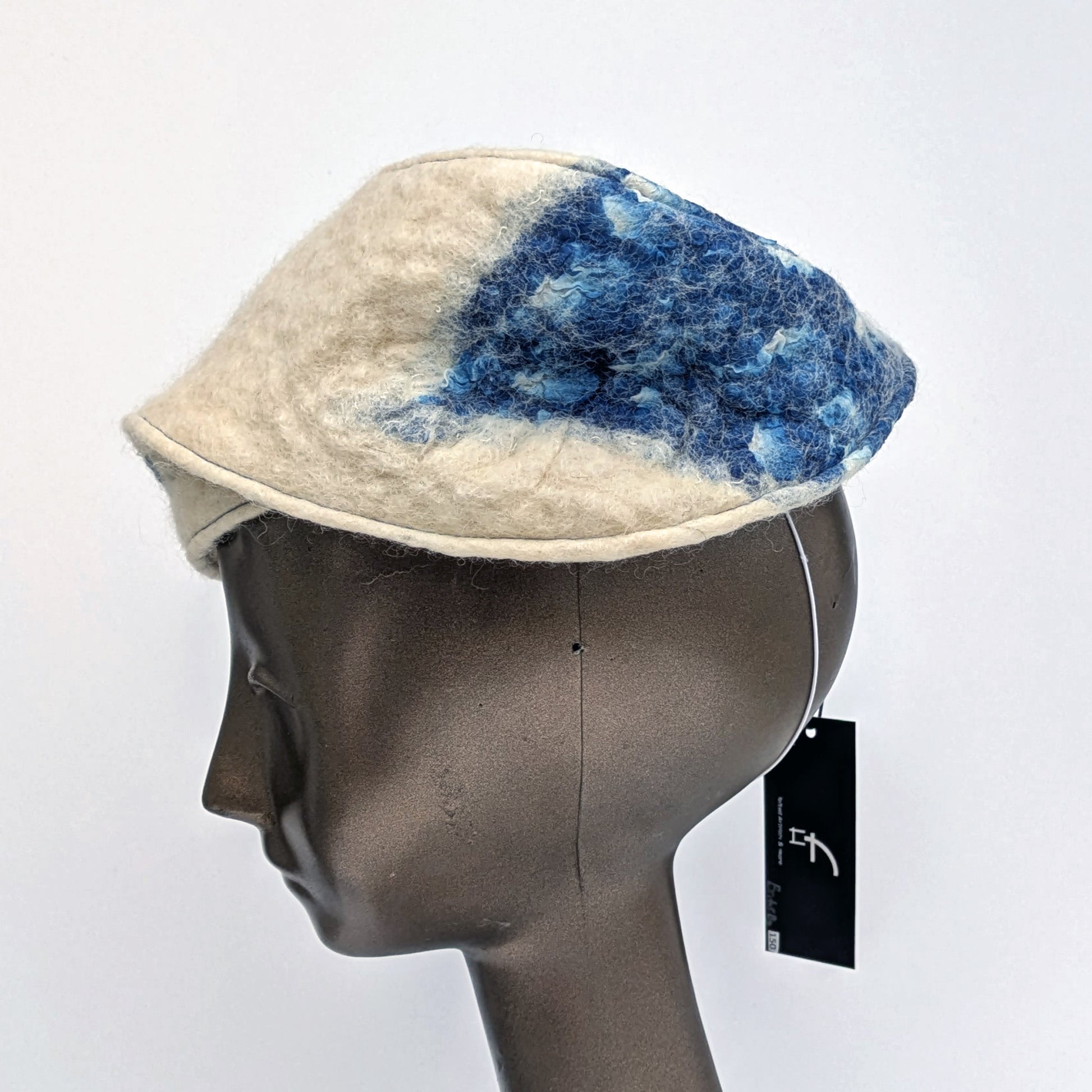Cream and blue patterned fascinator on a mannequin head against a white background