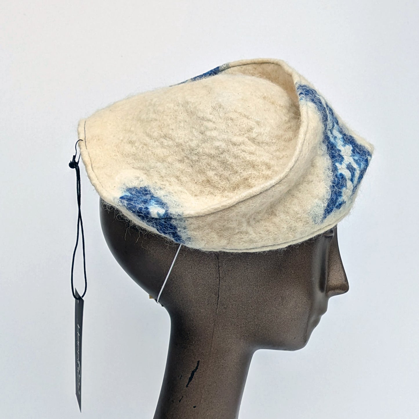 Cream and blue patterned fascinator on a mannequin head against a white background