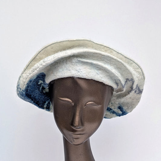 Creamy white felted hat with navy blue cyanotype printed seaweed towards the back of the hat.