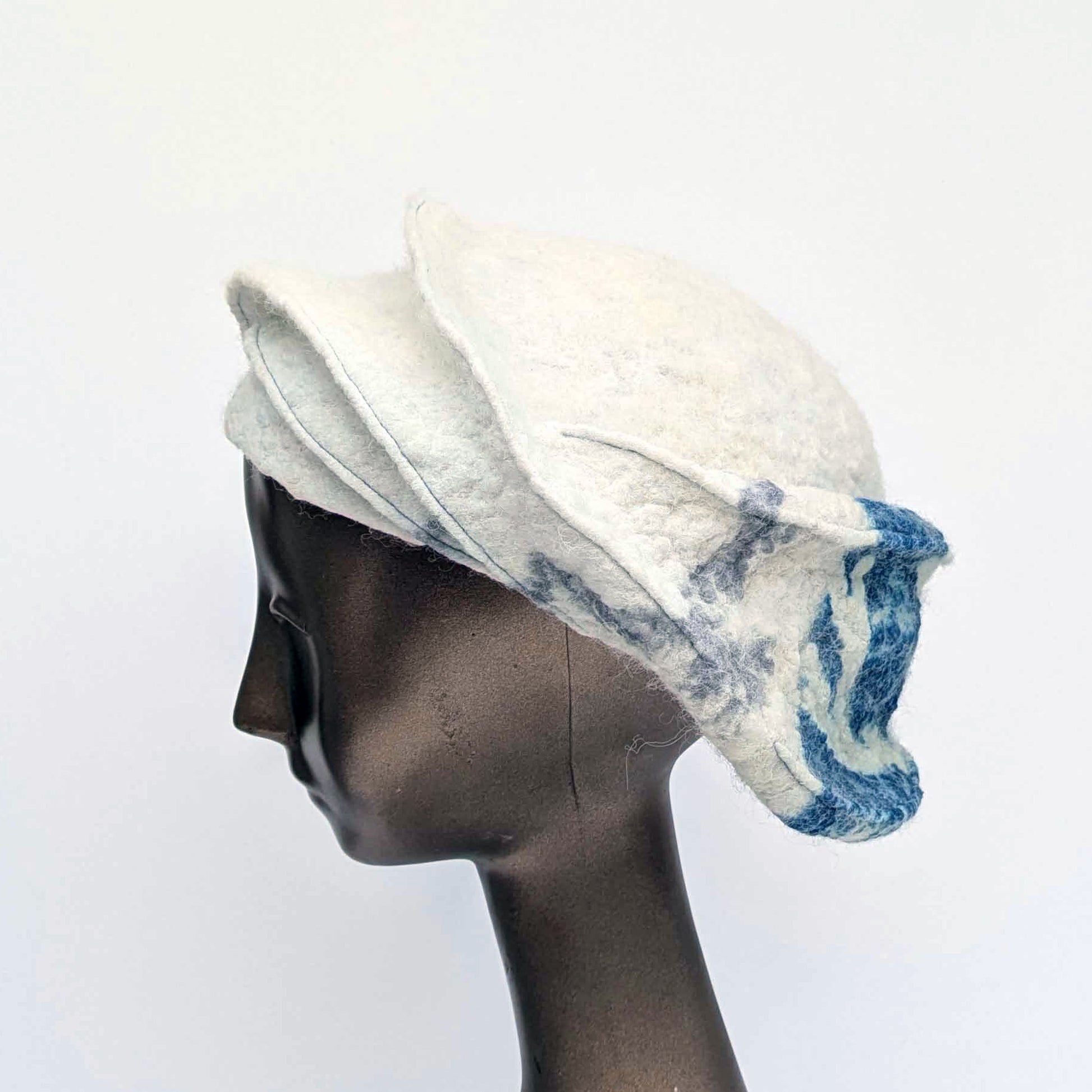 White and blue patterned hat on a mannequin head against a white background