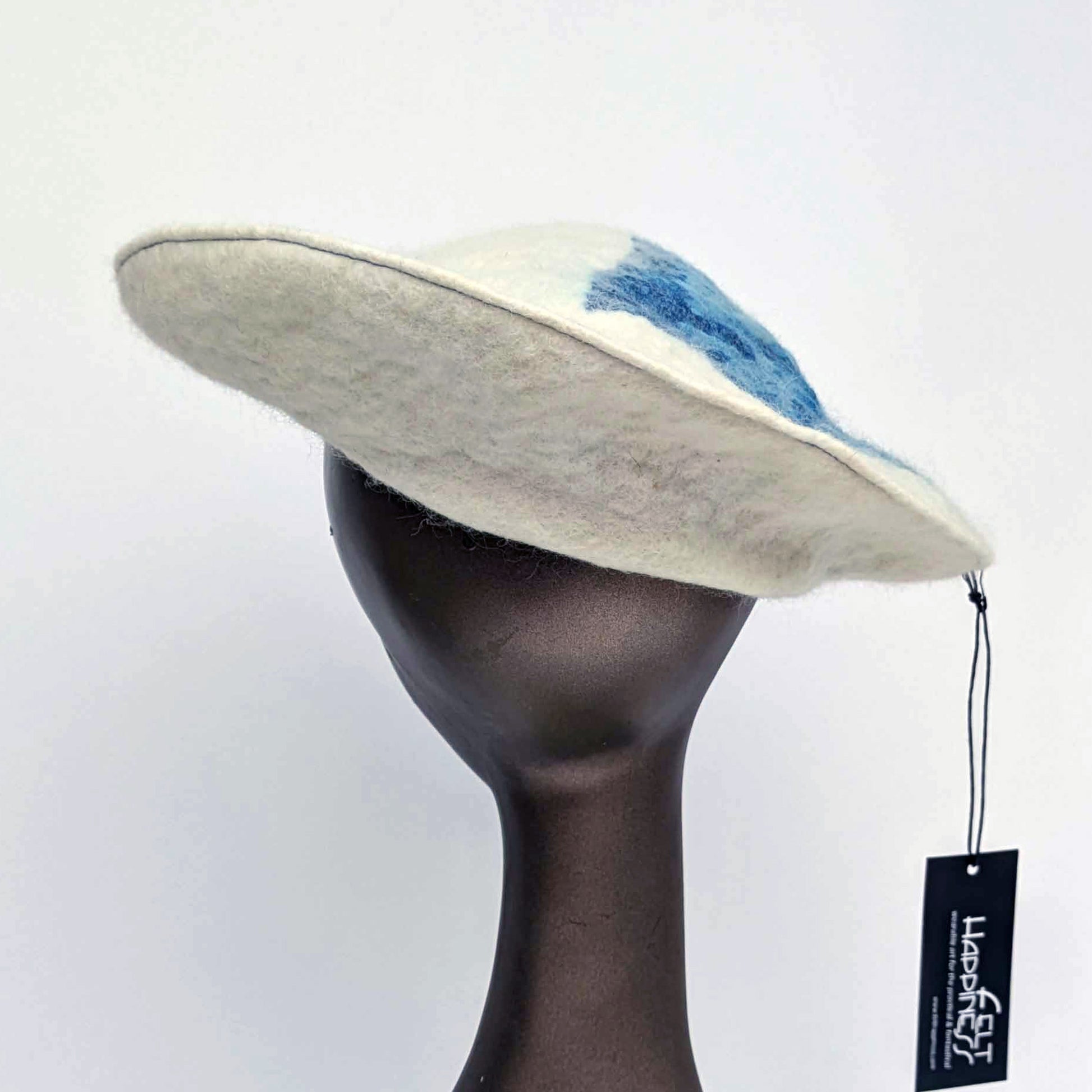 White beret with blue seaweed pattern on tipof hat - worn on mannequin - back view