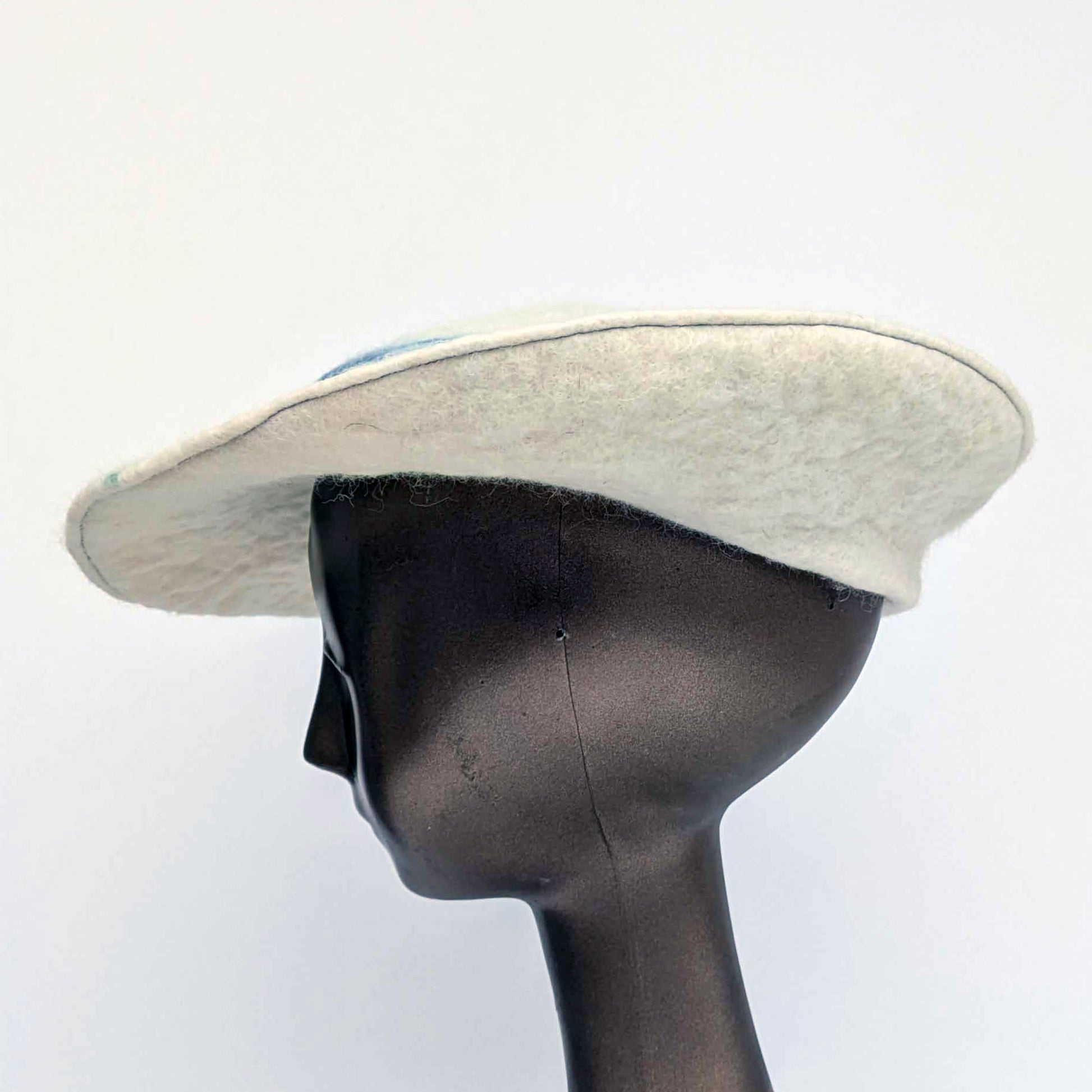 White beret with blue seaweed pattern on tip of hat - wornon mannequin -