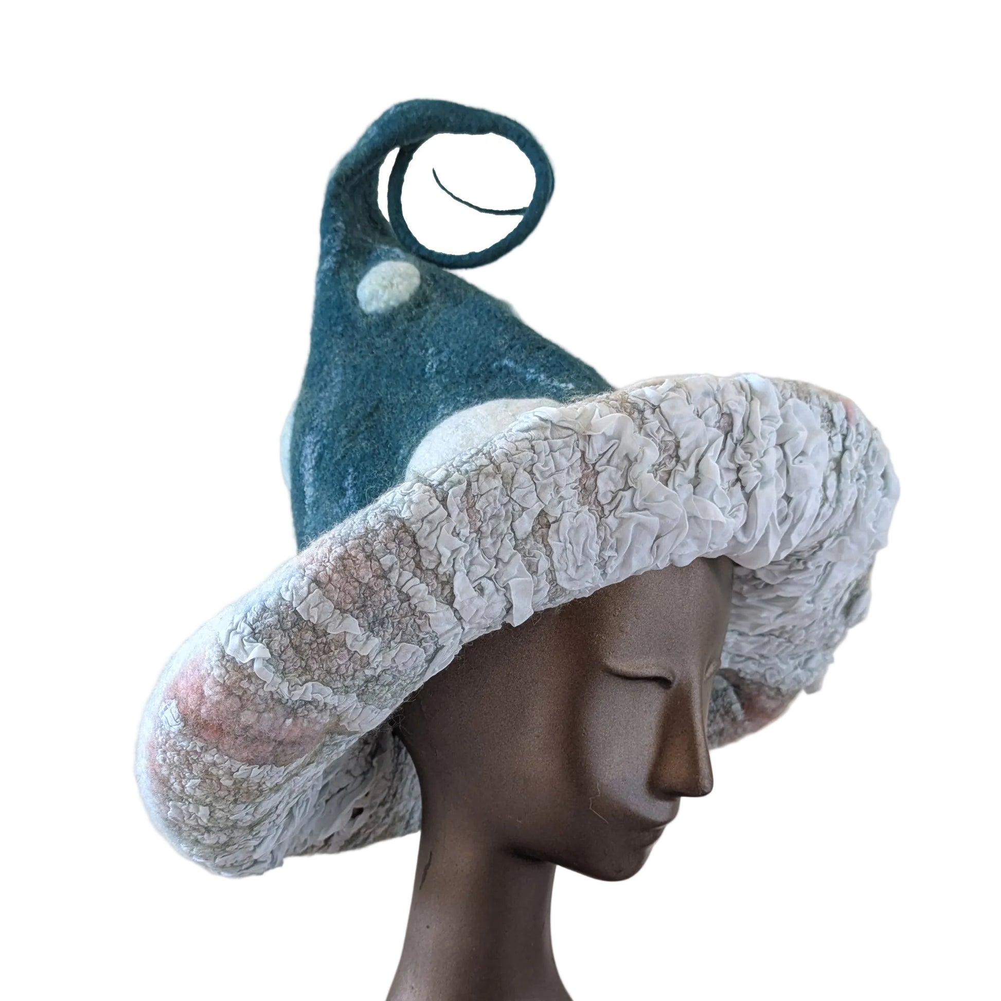 A whimsical felt hat shaped like a mushroom cap in blue-green with white spots, displayed on a mannequin head against a white background