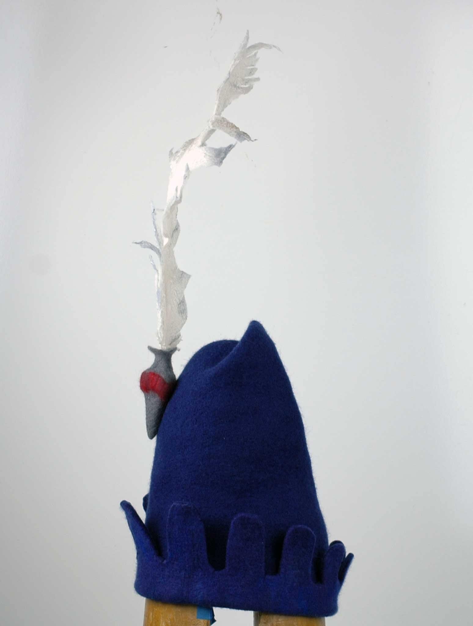 Blue Medieval Inspired Hat with detachable white feather in a gray felted vase - side view